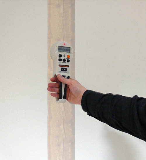 Dtecteur en train de reprer une barre en bois dans un mur.